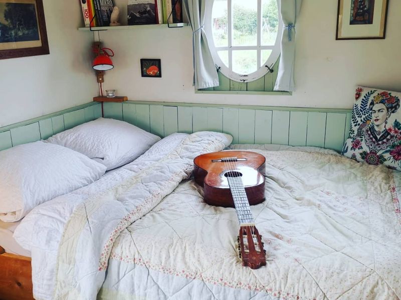 Gitarre liegt auf dem Doppelbett im Wiesenwagen