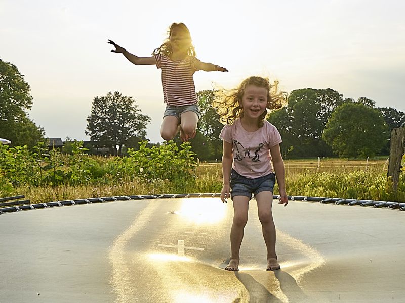 Kinder springen auf draußen auf einem Trampolin